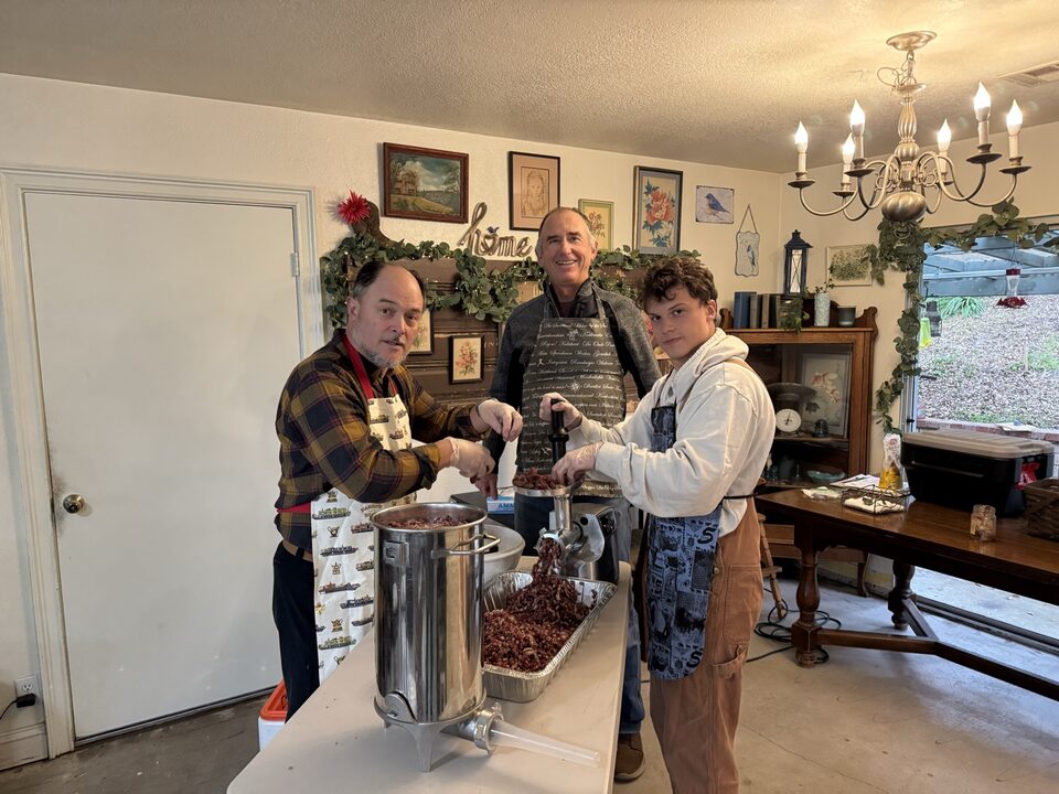 Ben in a kitchen with two others, making sausage